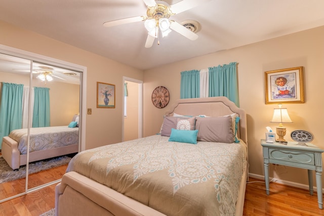 bedroom with a closet, wood finished floors, a ceiling fan, and baseboards