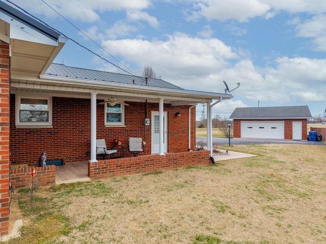 back of house with a garage, metal roof, a yard, an outdoor structure, and brick siding