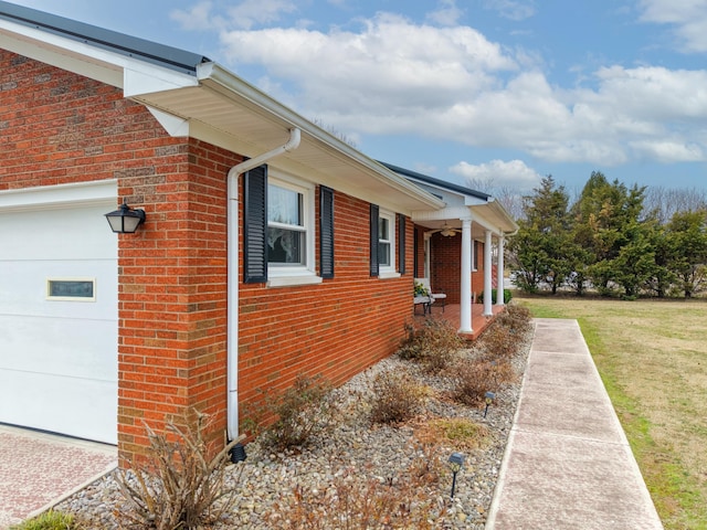 view of side of property featuring a garage, brick siding, and a lawn