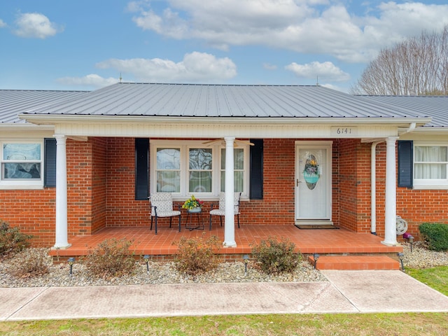 bungalow with covered porch, metal roof, and brick siding