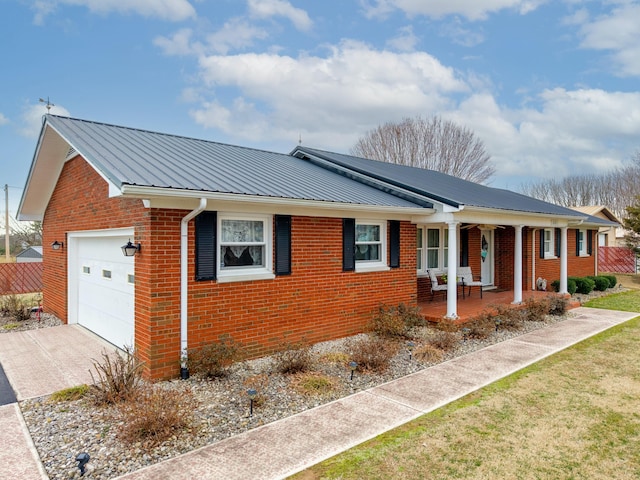 view of home's exterior featuring metal roof, an attached garage, covered porch, brick siding, and concrete driveway