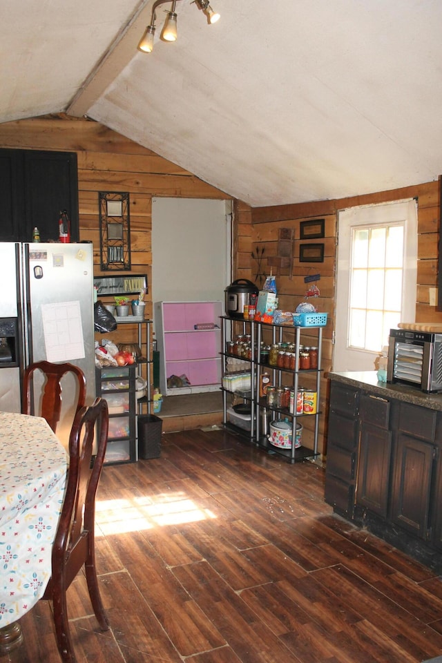 dining area featuring lofted ceiling with beams, wood walls, a toaster, and dark wood-style floors