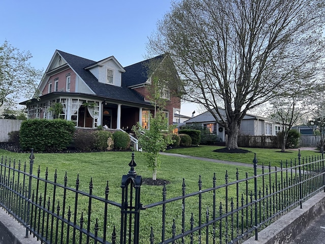 view of front facade with a front yard, brick siding, and fence private yard