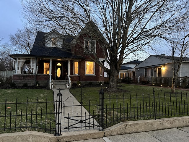 view of front of home featuring a fenced front yard, a front yard, a gate, and brick siding