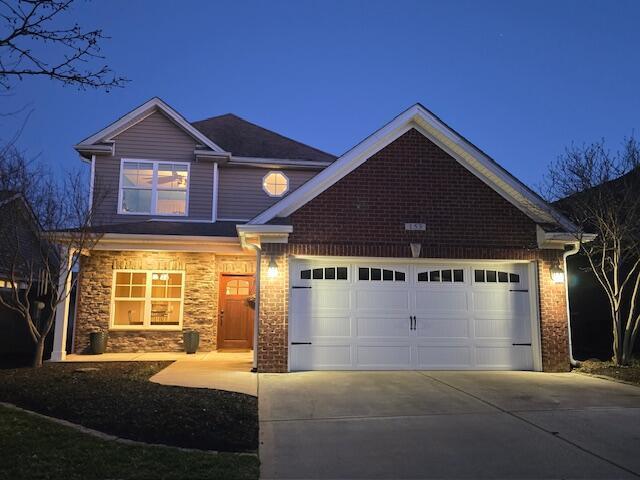 view of front of house with a garage, stone siding, and driveway