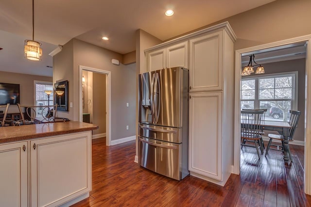 kitchen with dark wood-style floors, plenty of natural light, baseboards, and stainless steel refrigerator with ice dispenser