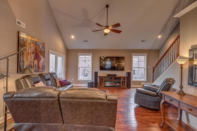 living area with a glass covered fireplace, a healthy amount of sunlight, stairway, and hardwood / wood-style floors