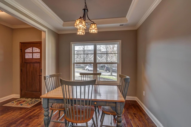 dining space featuring dark wood-type flooring, visible vents, baseboards, ornamental molding, and a tray ceiling