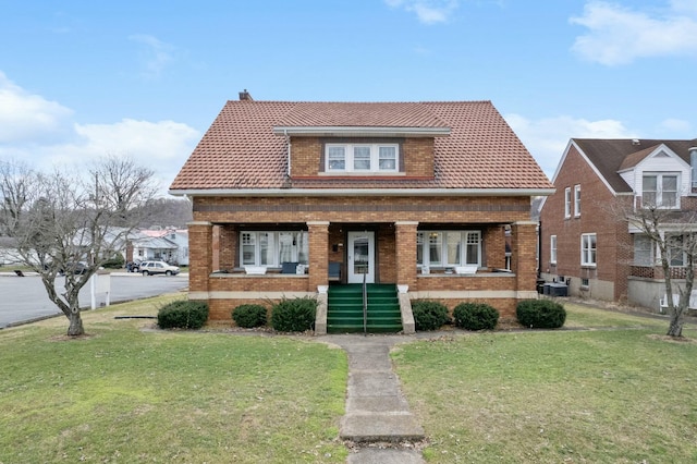 bungalow-style house featuring a porch, cooling unit, brick siding, a tile roof, and a front lawn