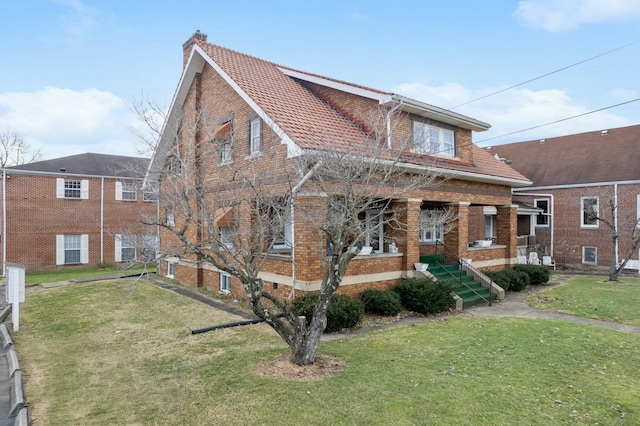 view of front of home featuring brick siding, a chimney, and a front yard