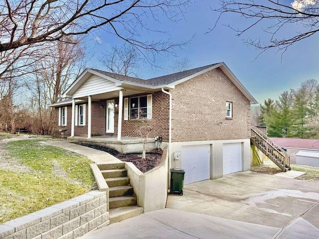 view of front of house with brick siding, covered porch, stairway, an attached garage, and driveway