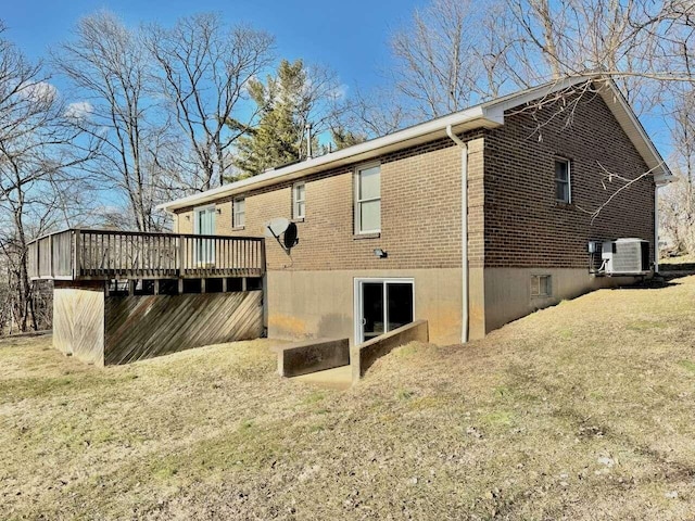 back of house with central air condition unit, a deck, a lawn, and brick siding