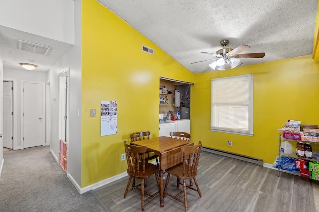 dining space featuring a baseboard heating unit, vaulted ceiling, visible vents, and washer and dryer