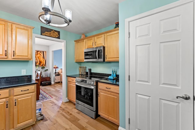 kitchen featuring light wood-style floors, appliances with stainless steel finishes, light brown cabinetry, dark countertops, and pendant lighting