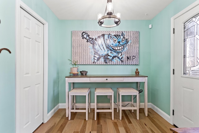 dining space featuring baseboards, light wood-style flooring, and an inviting chandelier