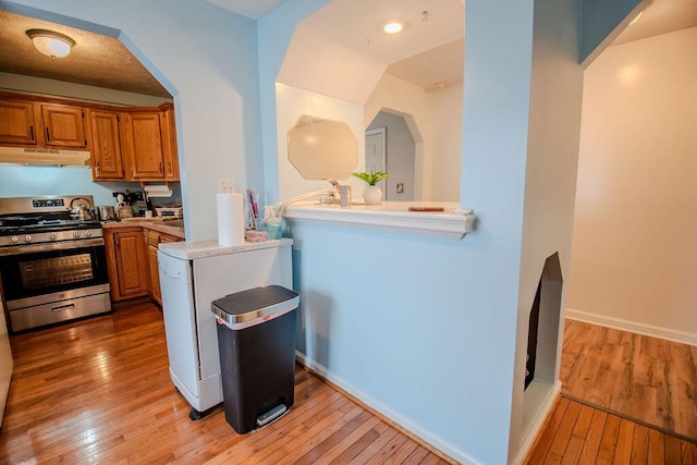 kitchen featuring stainless steel gas range oven, light wood-type flooring, and under cabinet range hood