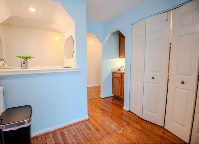 kitchen with light countertops, brown cabinets, light wood-style flooring, and baseboards