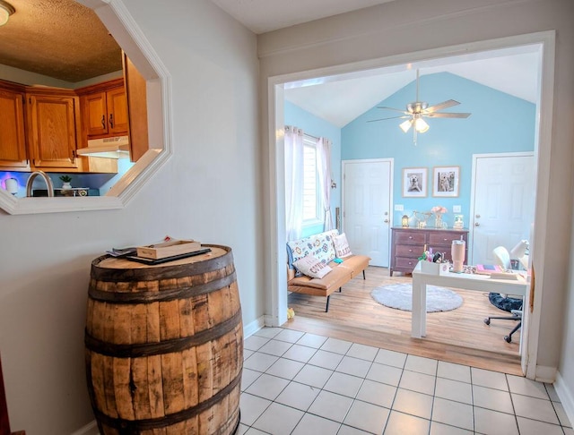 interior space featuring tile patterned flooring, vaulted ceiling, baseboards, and ceiling fan