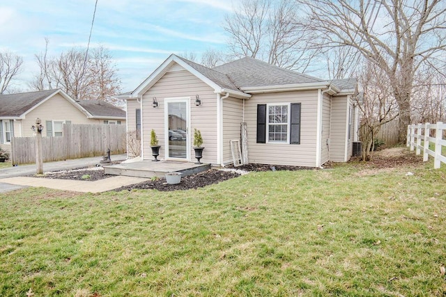 rear view of property with a shingled roof, fence, and a lawn