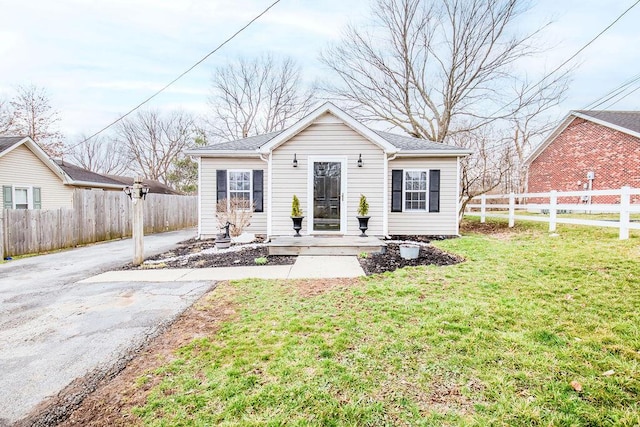 bungalow featuring driveway, a front lawn, and fence