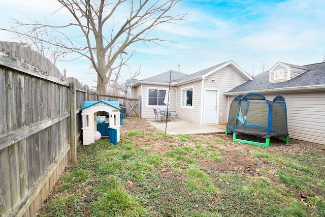 rear view of house with a patio area, a fenced backyard, and a trampoline