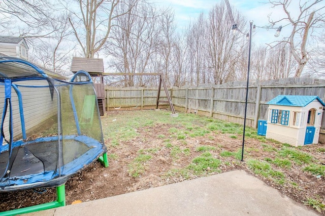 view of yard with a trampoline, an outbuilding, a fenced backyard, and a shed