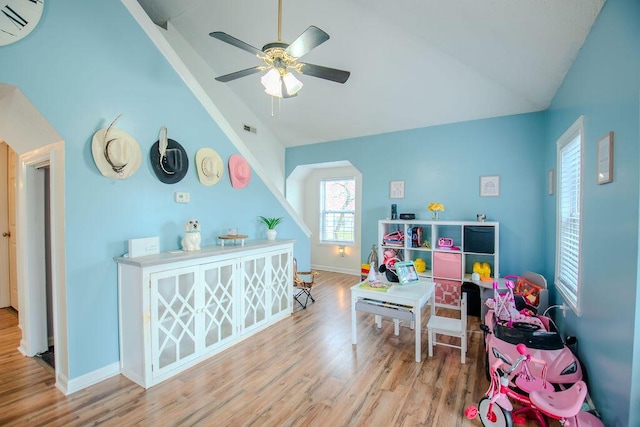 playroom featuring lofted ceiling, wood finished floors, a ceiling fan, baseboards, and an AC wall unit