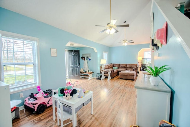 living room featuring lofted ceiling, ceiling fan, light wood-type flooring, and baseboards