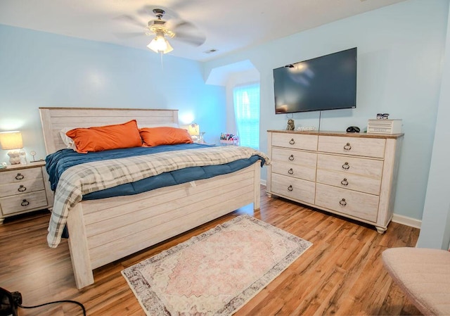 bedroom with a ceiling fan, baseboards, visible vents, and light wood finished floors