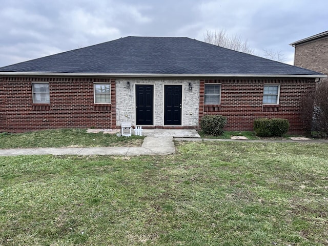 back of house featuring a yard, a shingled roof, and brick siding