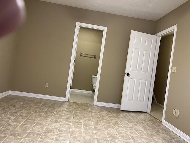 unfurnished bedroom with ensuite bath and baseboards