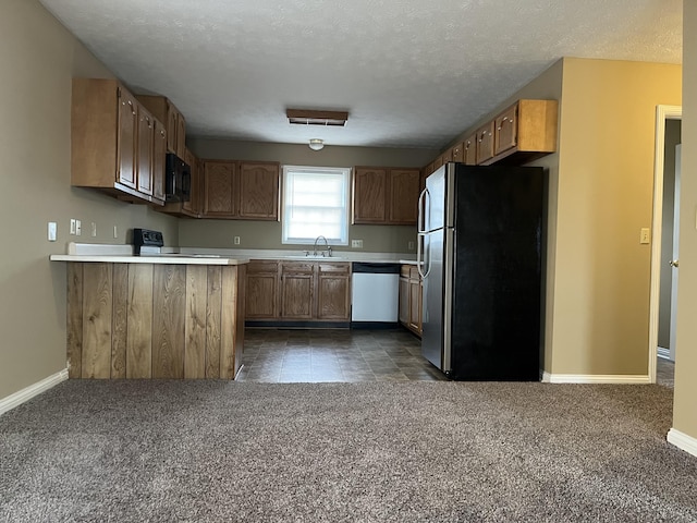 kitchen with stainless steel appliances, a peninsula, a sink, baseboards, and light countertops