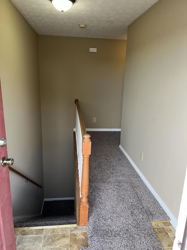 stairs featuring a textured ceiling, carpet floors, and baseboards