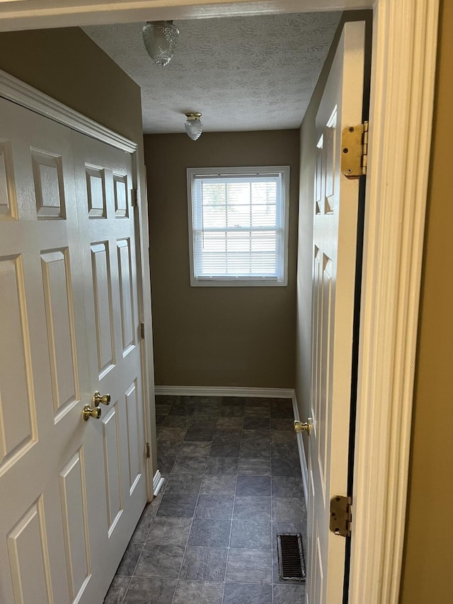 interior space with visible vents, a textured ceiling, and baseboards