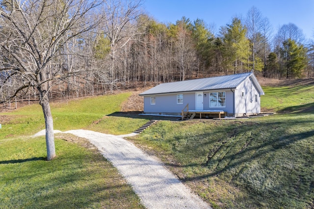 view of front of property featuring metal roof, aphalt driveway, and a front lawn