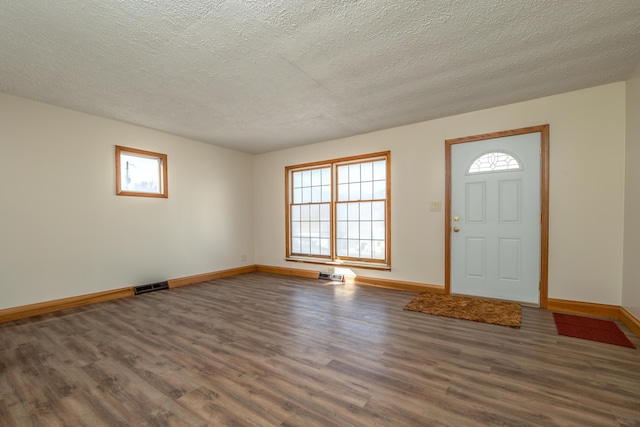 foyer featuring a textured ceiling, baseboards, and wood finished floors