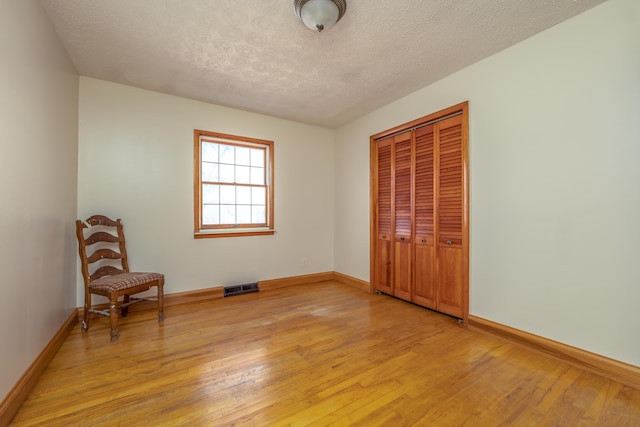 unfurnished bedroom with a closet, light wood-type flooring, visible vents, and baseboards