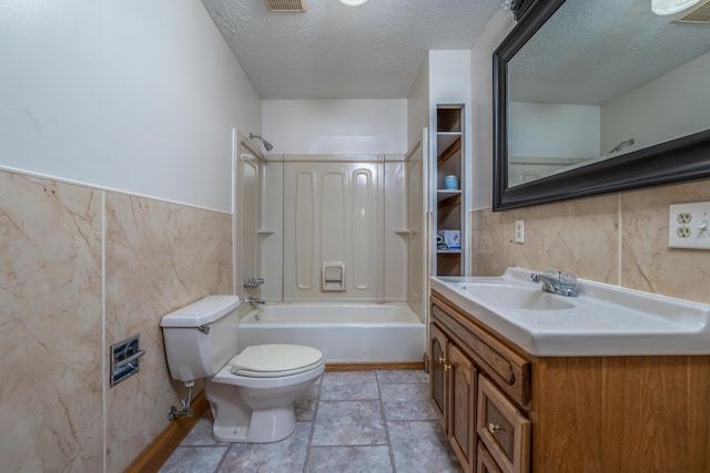 full bathroom with tile walls, toilet, a textured ceiling, vanity, and  shower combination