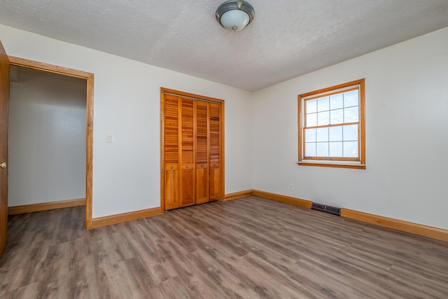 unfurnished bedroom with baseboards, visible vents, a closet, and wood finished floors