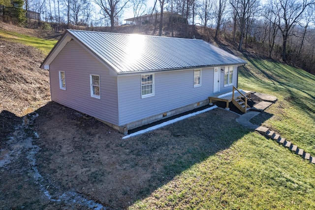 view of property exterior featuring metal roof and a lawn