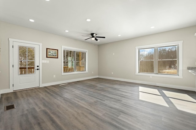 unfurnished living room featuring baseboards, wood finished floors, a wealth of natural light, and recessed lighting