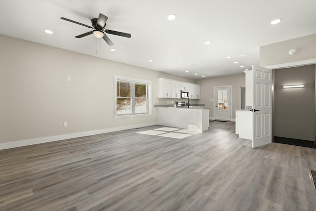 unfurnished living room featuring light wood finished floors, plenty of natural light, and baseboards