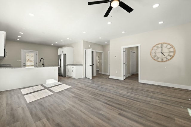 unfurnished living room featuring dark wood-style flooring, a sink, and recessed lighting