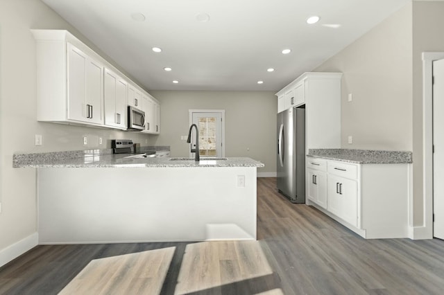 kitchen with appliances with stainless steel finishes, a sink, a peninsula, and light stone counters