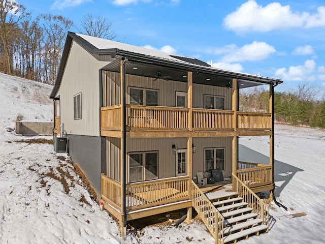 snow covered house with a balcony, ceiling fan, and stairway