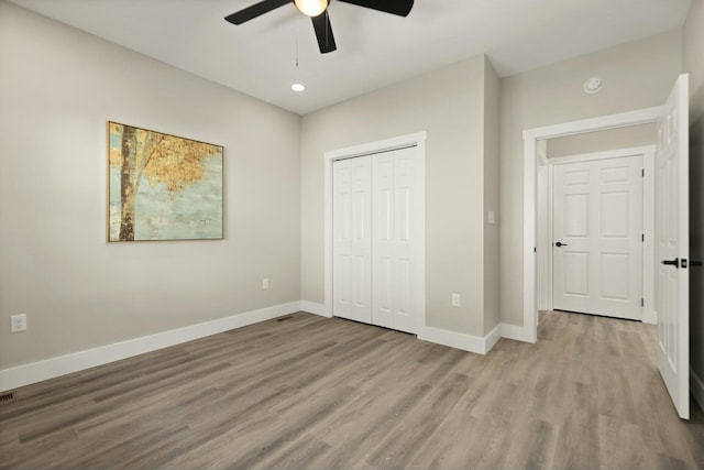 unfurnished bedroom with ceiling fan, a closet, light wood-style flooring, and baseboards