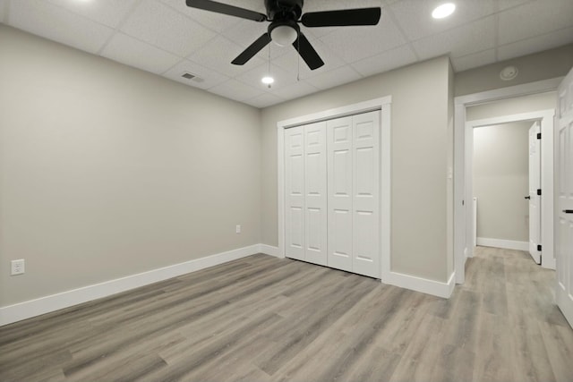 unfurnished bedroom with baseboards, visible vents, a paneled ceiling, light wood-style floors, and a closet