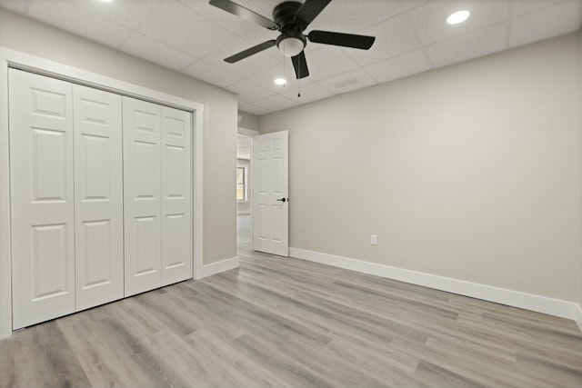 unfurnished bedroom featuring a paneled ceiling, light wood finished floors, visible vents, and baseboards