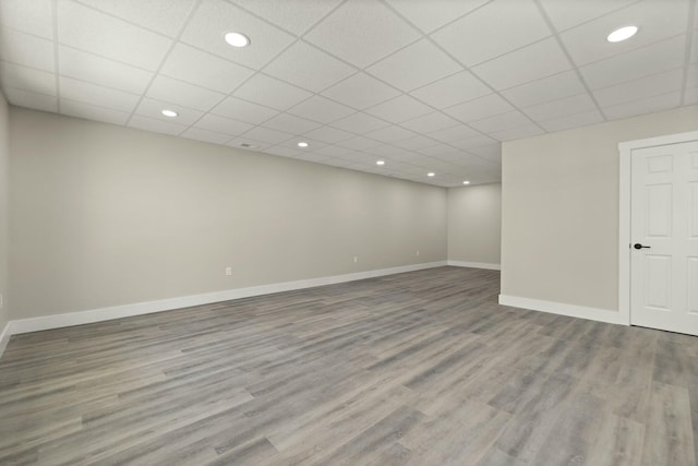 finished basement featuring light wood-style floors, a drop ceiling, and baseboards