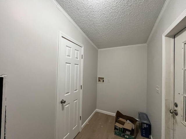 hallway with a textured ceiling, ornamental molding, wood finished floors, and baseboards